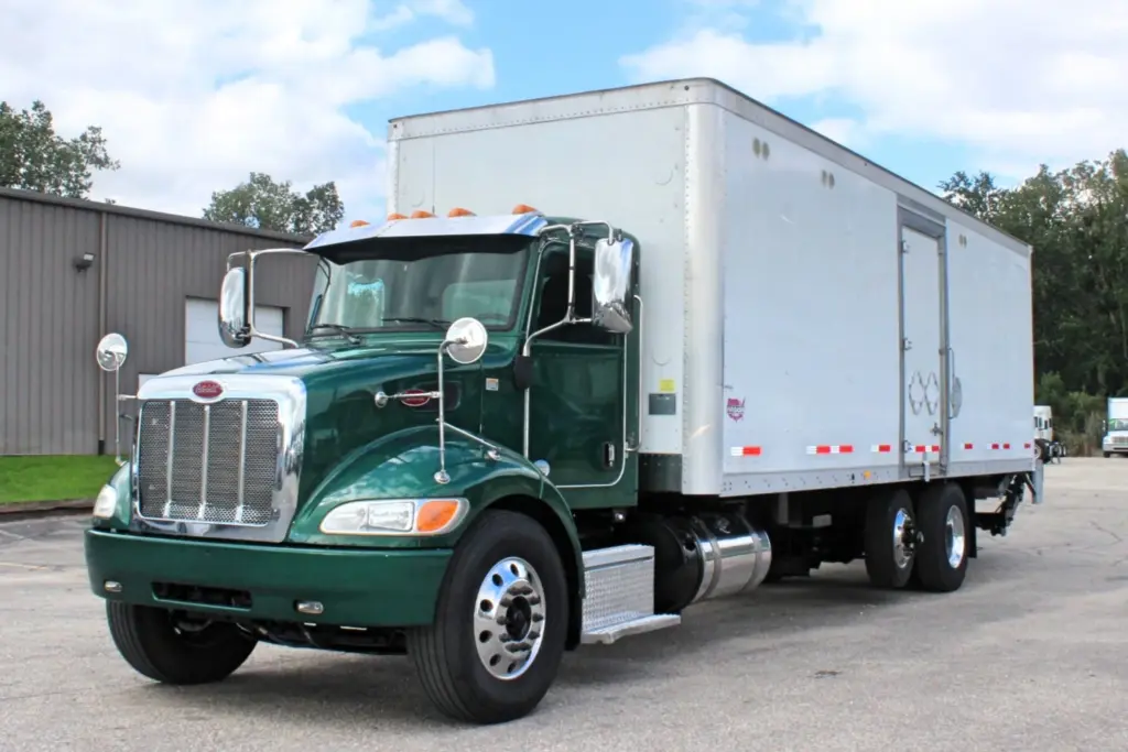 2018 Peterbilt 348 box truck – front driver-side view with green cab and white cargo box