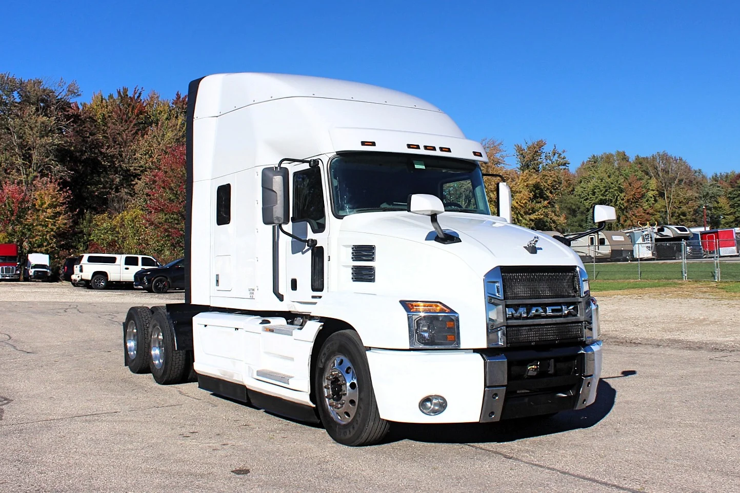 2023 Mack Anthem — front passenger-side view of white sleeper tractor with chrome wheels parked on gravel lot under blue sky
