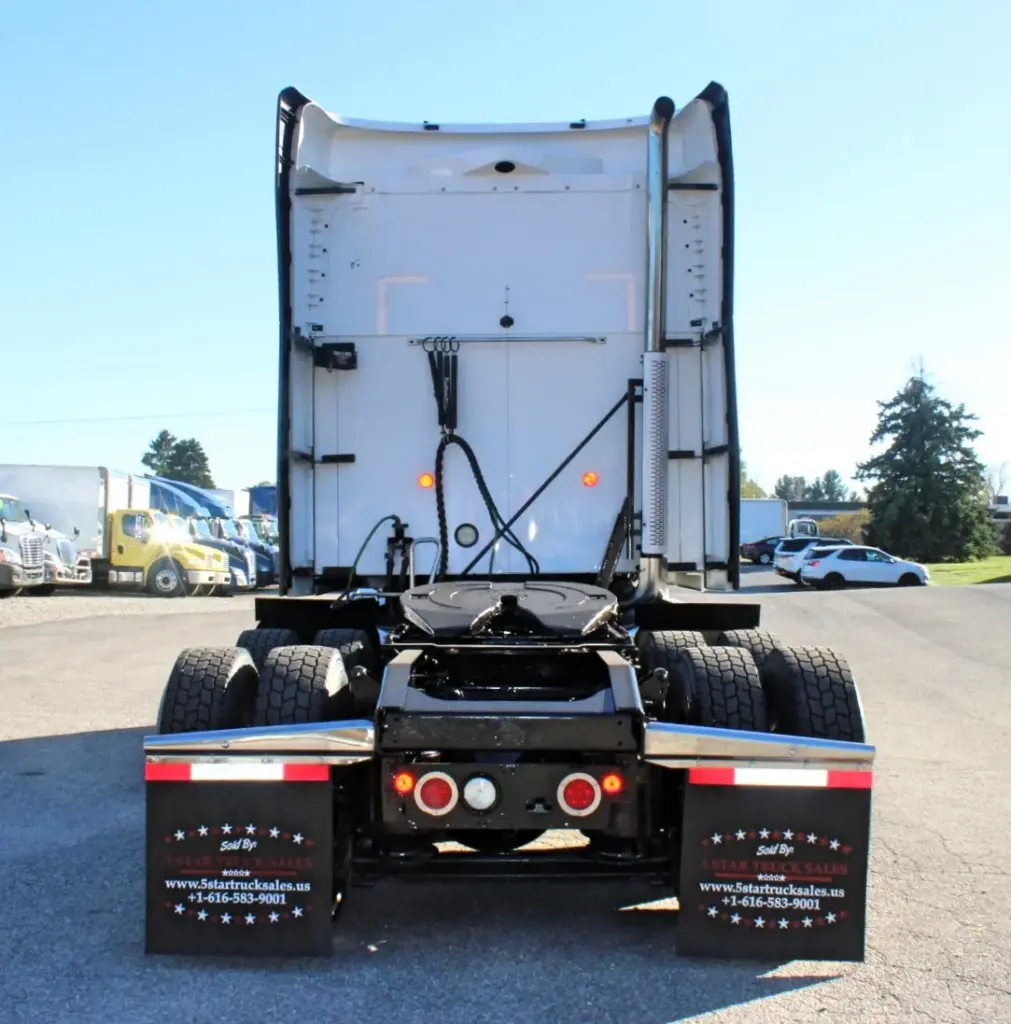2023 Mack Anthem — straight rear view of white sleeper cab, bare fifth wheel, red taillights, chrome fenders and black mud flaps