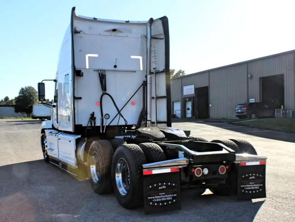 2023 Mack Anthem — driver-side rear angle of white sleeper tractor on pavement, showing air lines, polished wheels and mud flaps