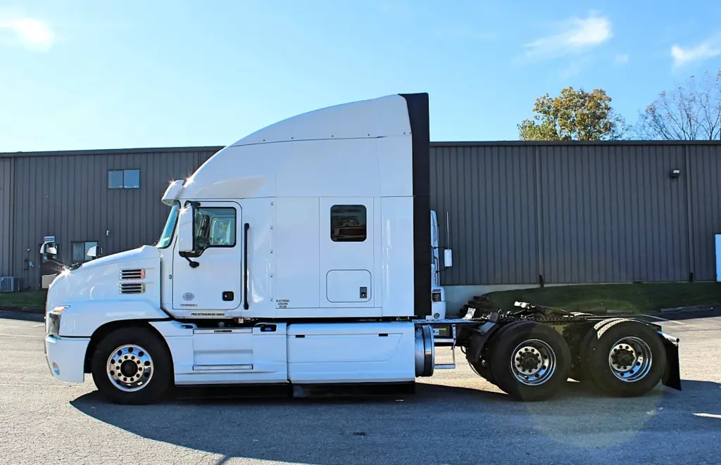 2023 Mack Anthem — left-facing side profile of white sleeper tractor with tall roof fairing, tandem axles and chrome wheels