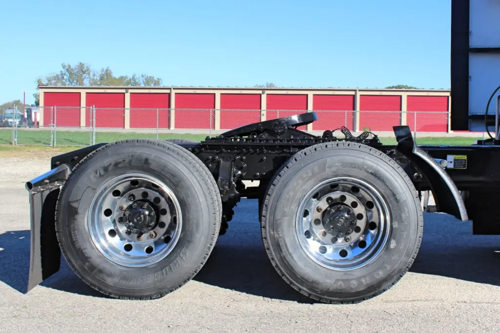 2023 Mack Anthem — close side view of tandem rear axles, polished aluminum wheels, fifth wheel plate and black frame