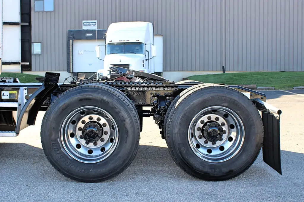2023 Mack Anthem — side view of tandem drive axles with polished wheels, black frame and fifth wheel plate, mud flap at right