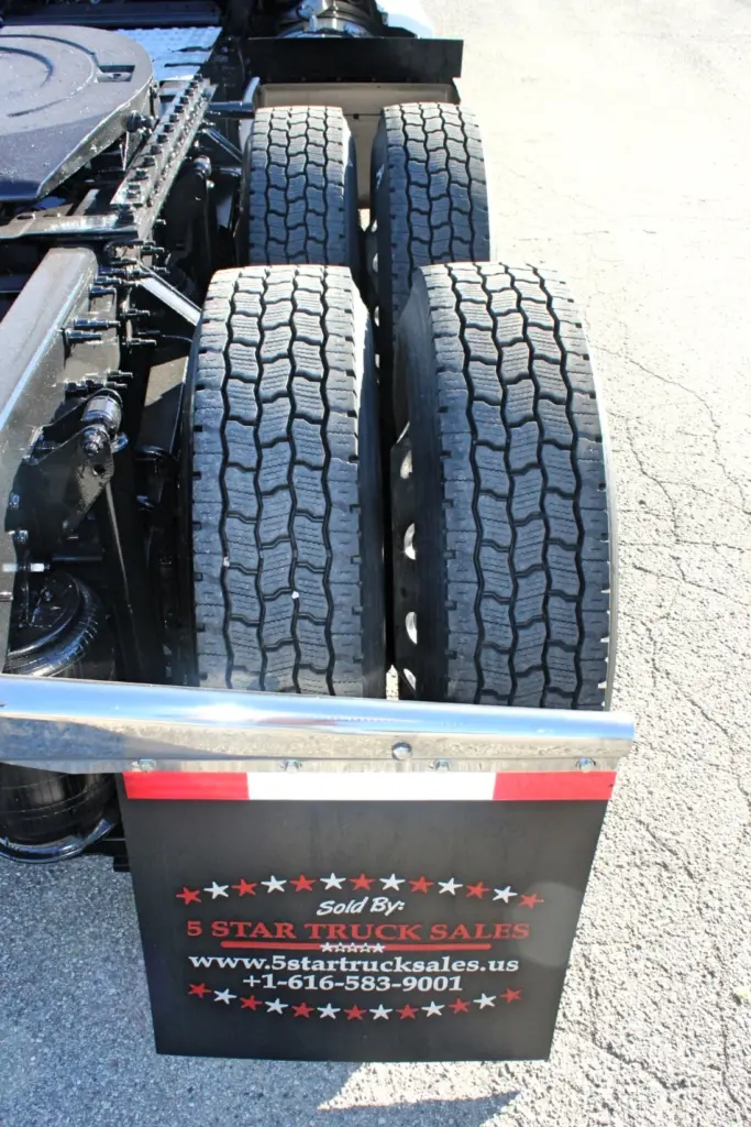 2023 Mack Anthem — top-down view of dual rear drive tires with deep tread, fifth wheel and chrome fender rail above a black mud flap