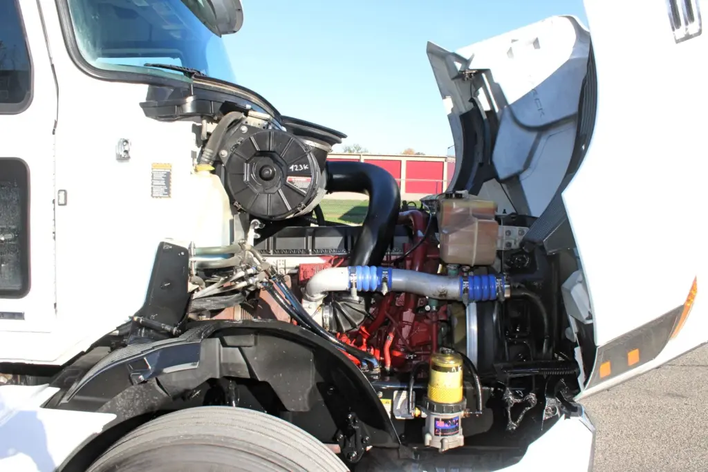 2023 Mack Anthem — side view of tilted hood with air filter housing, blue coolant hoses, coolant tank and fuel filter beside front tire