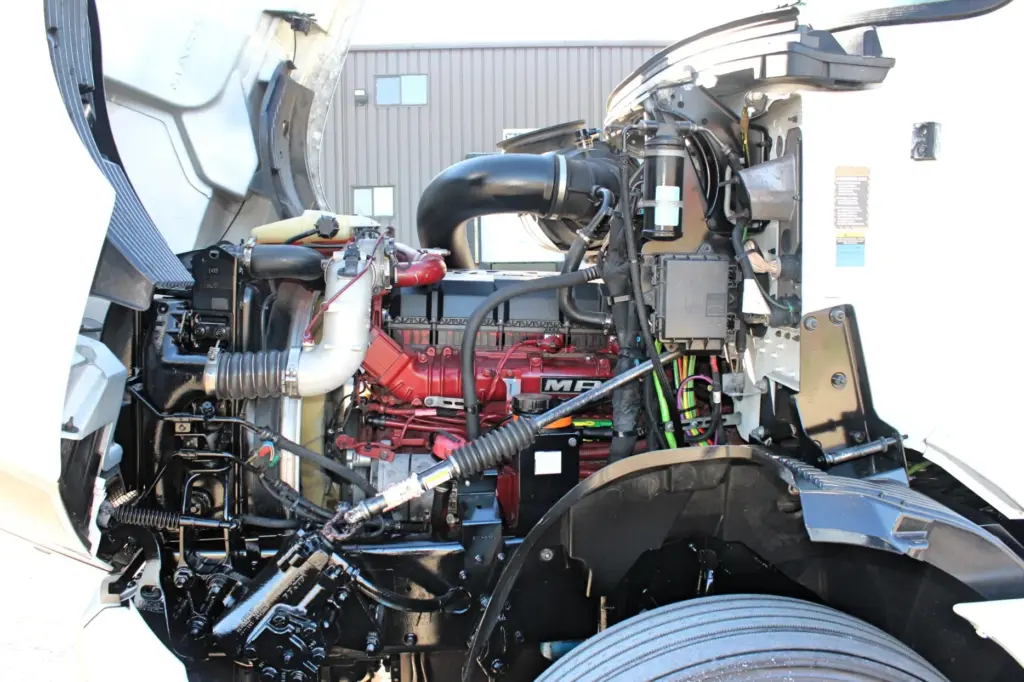 2023 Mack Anthem — open hood showing red MACK MP8 engine, black intake pipe, hoses, steering linkage and front tire