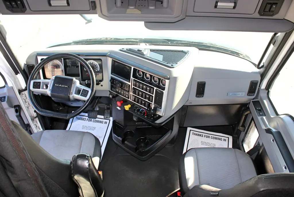 2023 Mack Anthem — view from the driver door of the front cab, showing both gray seats, dash, steering wheel and floor mats