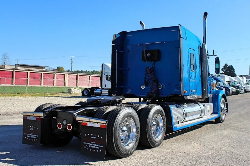 2016 Freightliner Coronado 132 — rear three-quarter view of blue sleeper with mud flaps and aluminum wheels on the drive axles
