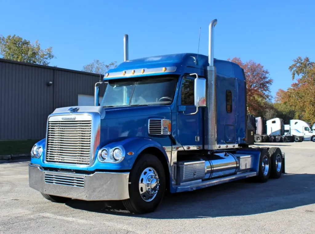 2016 Freightliner Coronado 132 — angled view from the front of a blue sleeper with chrome grille and bumper in sunlight