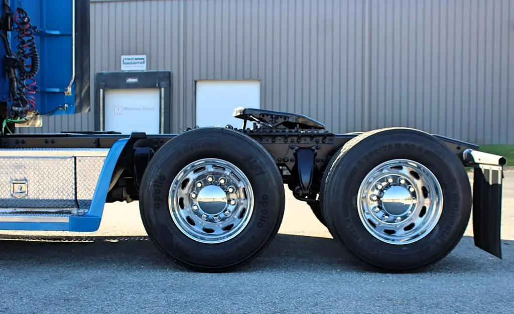 2016 Freightliner Coronado 132 — side view of tandem drive wheels with polished aluminum rims and blue fender