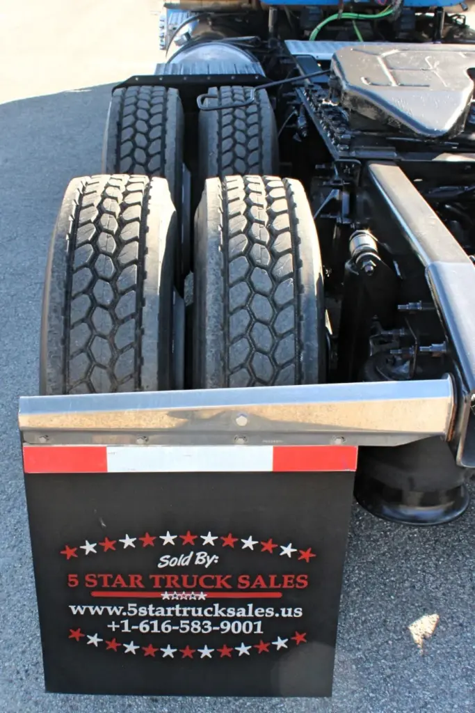 2016 Freightliner Coronado 132 — low rear view of dual tandem drive tires, black tread and mud flap below the sleeper frame