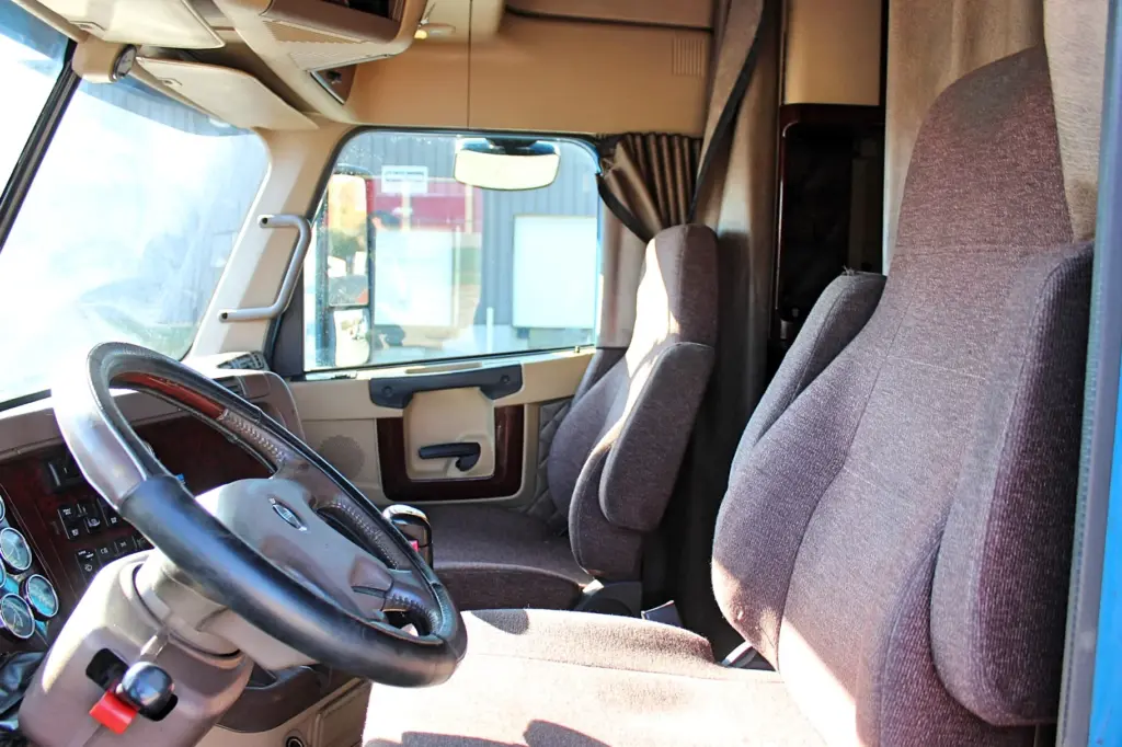 2016 Freightliner Coronado 132 — interior view of cab with black steering wheel and brown cloth seats