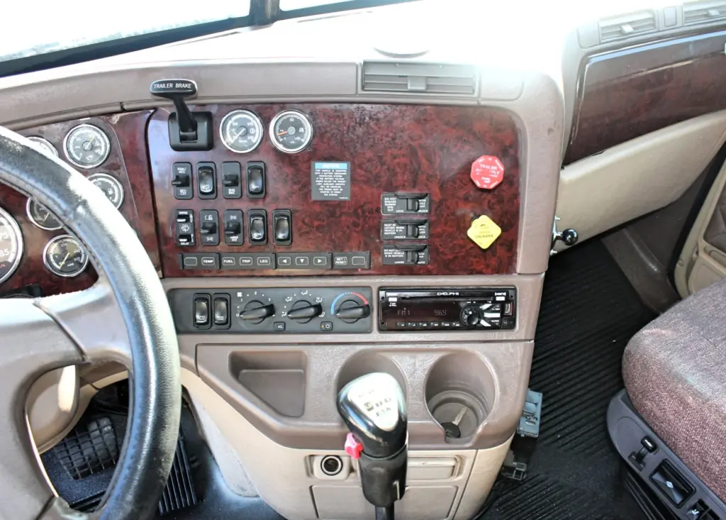 2016 Freightliner Coronado 132 — wood-grain switch panel, trailer brake lever and gauges above the radio in cab