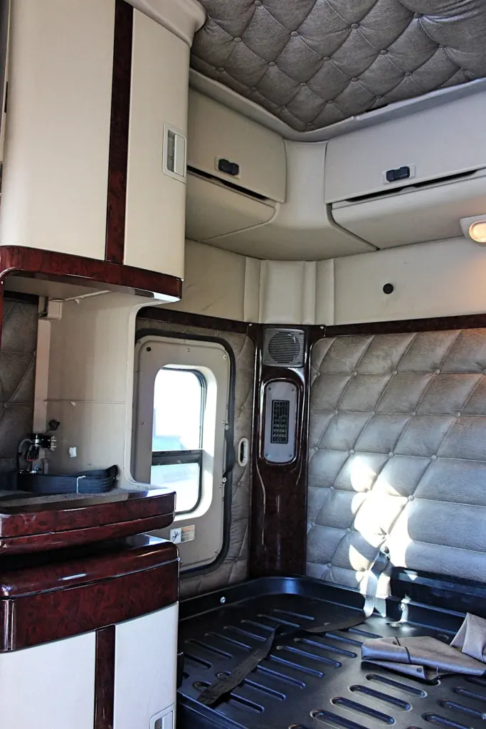 2016 Freightliner Coronado 132 — sleeper interior toward a side window, quilted gray walls and wood-grain cabinet trim