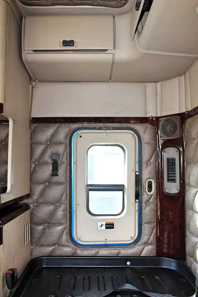 2016 Freightliner Coronado 132 — straight-on view of sleeper rear wall with centered window door and wood-grain vent trim