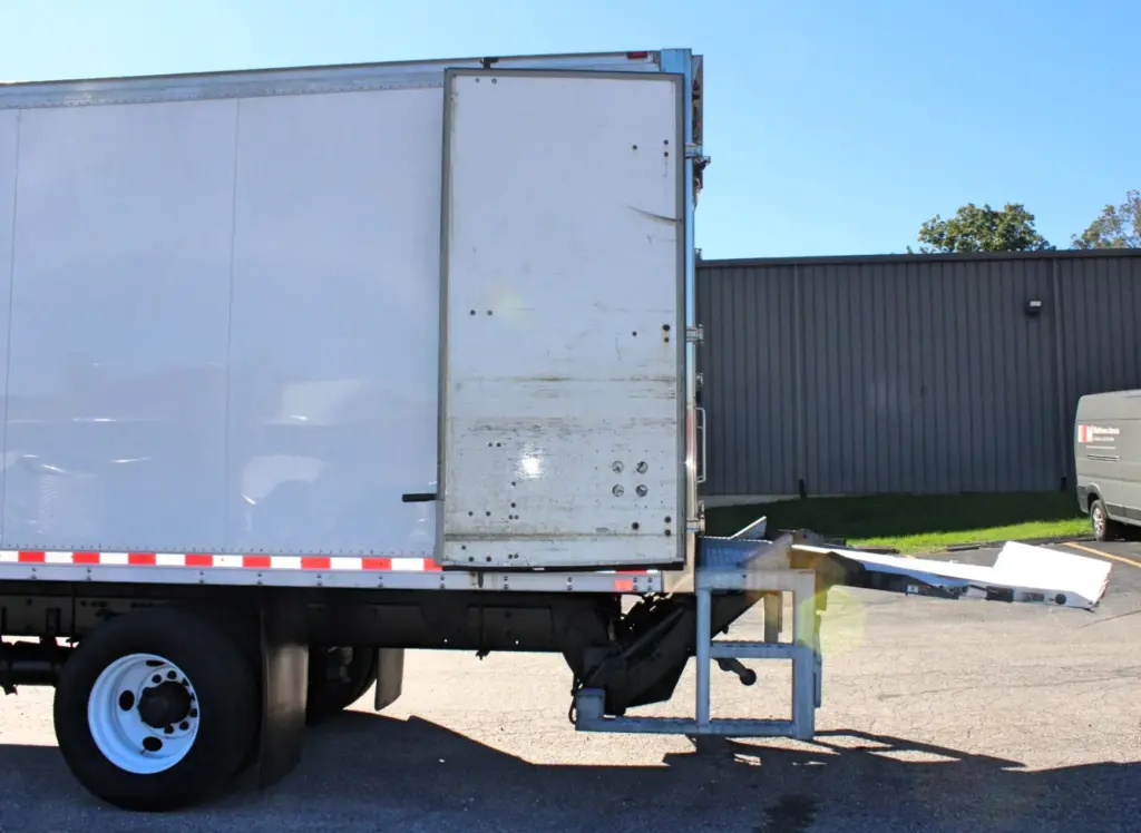 2016 Freightliner M2-106 Box Truck – opposite rear-side view with one cargo door open and hydraulic liftgate extended behind the box.