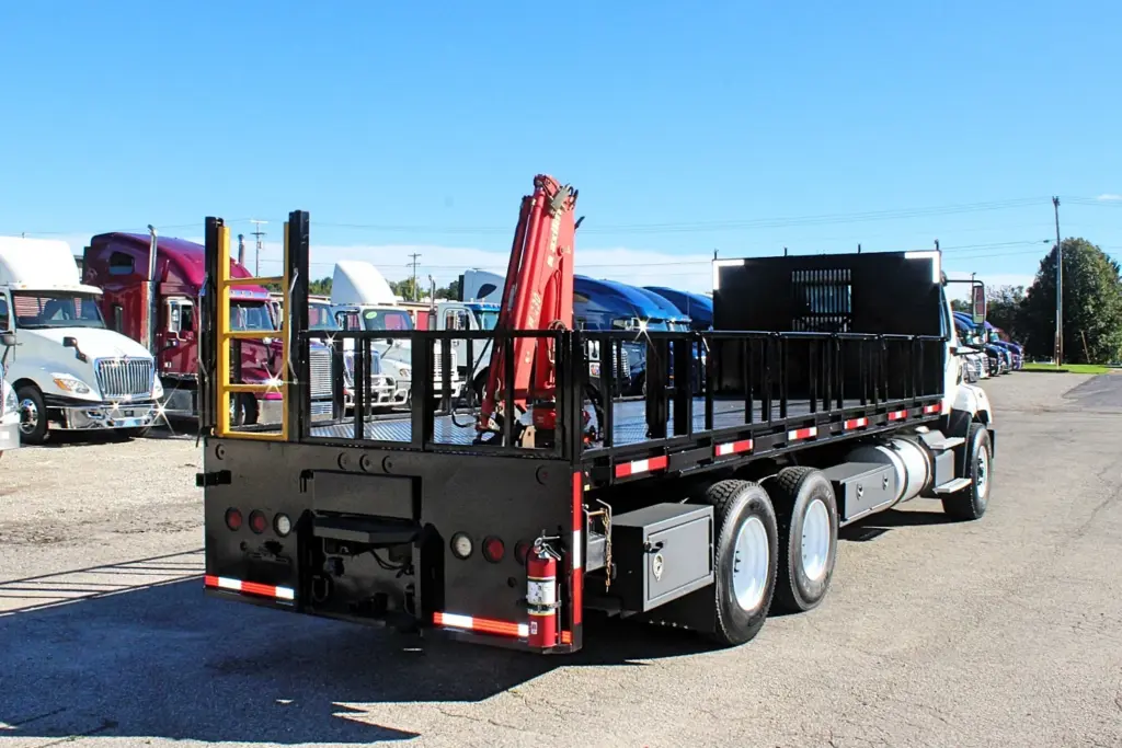2018 Freightliner 114SD – rear three-quarter view of flatbed crane truck with tandem axles and stake sides.