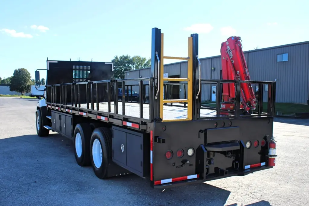 2018 Freightliner 114SD – driver-side rear view of tandem axle flatbed truck with knuckle boom crane.
