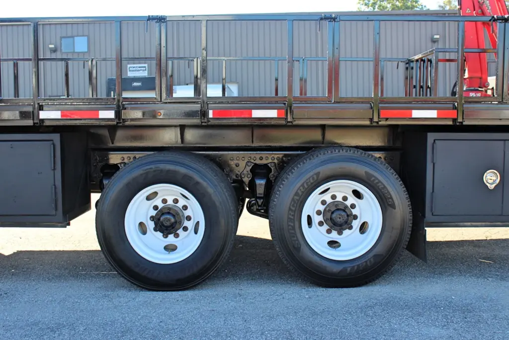 2018 Freightliner 114SD – close-up of tandem rear axles, dual tires and white steel wheels.