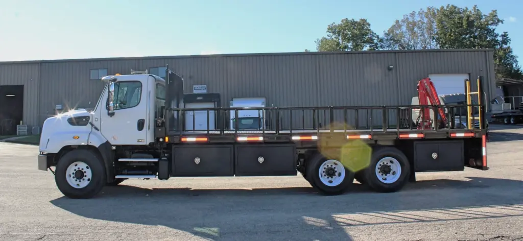 2018 Freightliner 114SD – full driver-side profile of heavy-duty stake bed truck with rear-mounted crane.