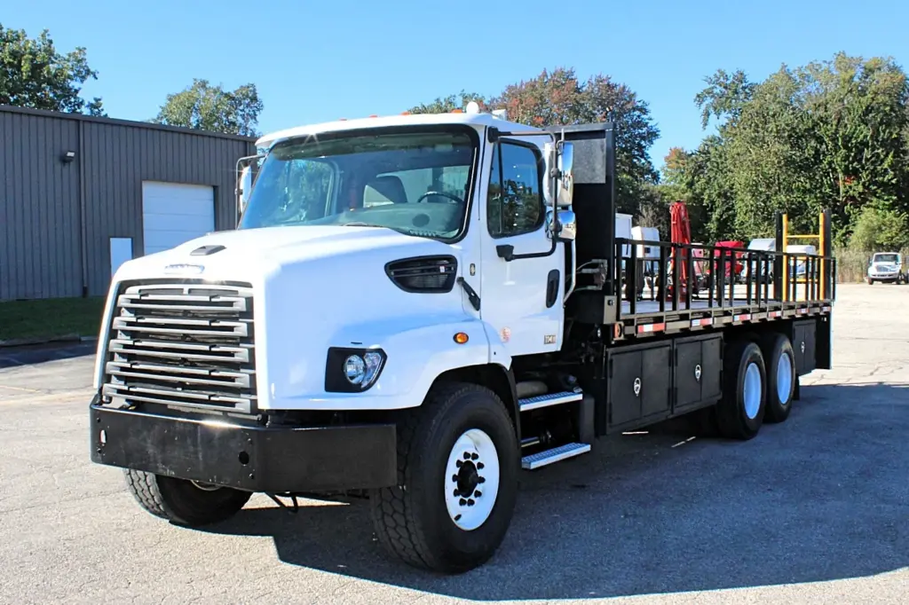 2018 Freightliner 114SD – front driver-side view of white vocational flatbed crane truck.