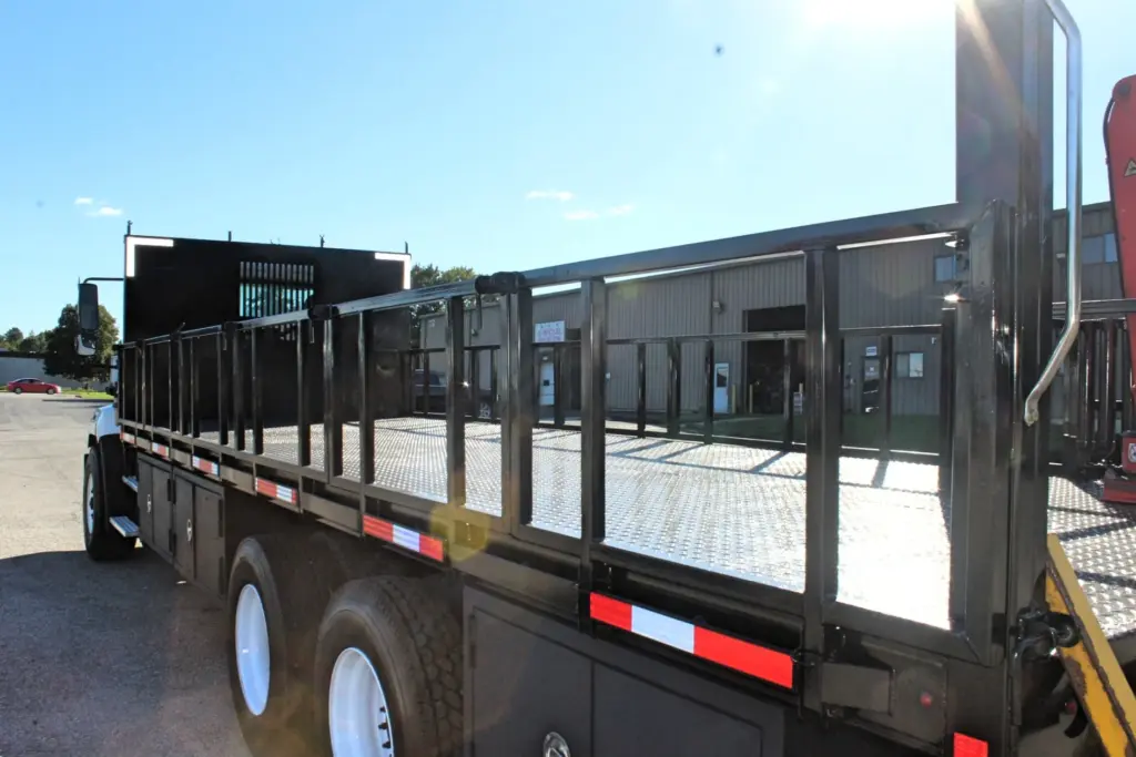 2018 Freightliner 114SD – heavy-duty flatbed with hinged stake sides and diamond plate steel deck.