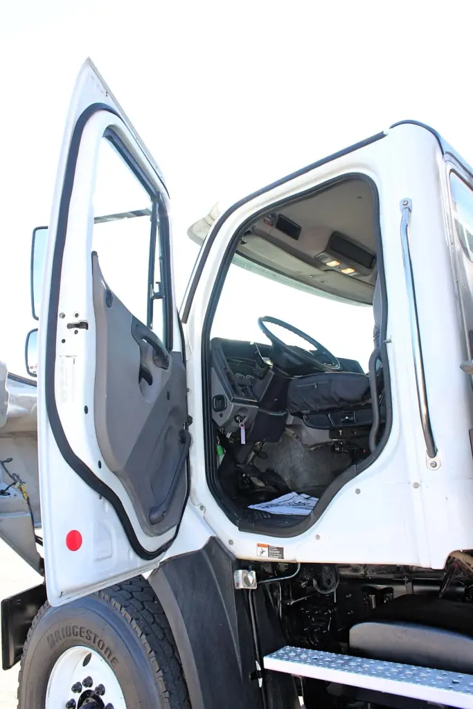 2018 Freightliner 114SD – open driver door showing cab entry, driver seat and dashboard.