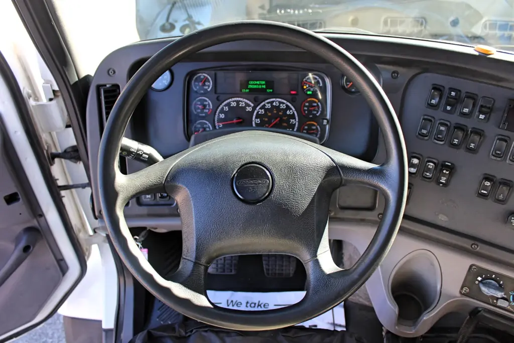 2018 Freightliner 114SD – driver cockpit with Freightliner steering wheel, gauges and dashboard controls.