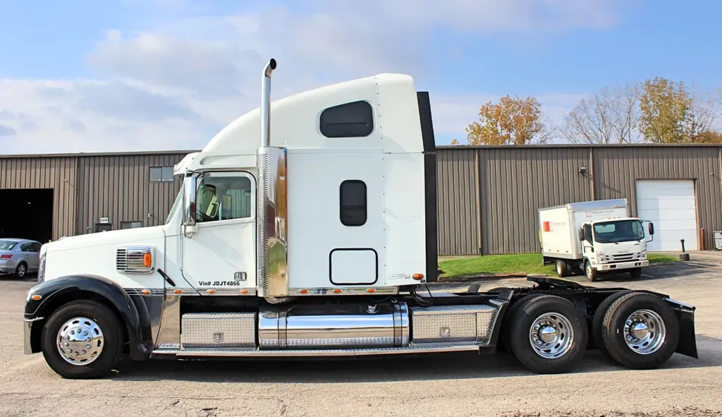 2018 Freightliner Coronado 132 — full side view of white sleeper tractor with polished exhaust stack and tandem axles