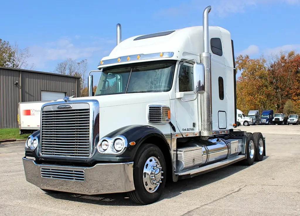 2018 Freightliner Coronado 132 — angled view of white sleeper with black fenders, chrome bumper and tall exhaust stacks.