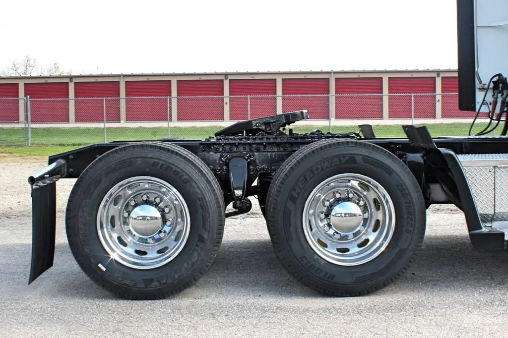 2018 Freightliner Coronado 132 — low side angle of tandem drive axles with polished aluminum wheels and black mud flap