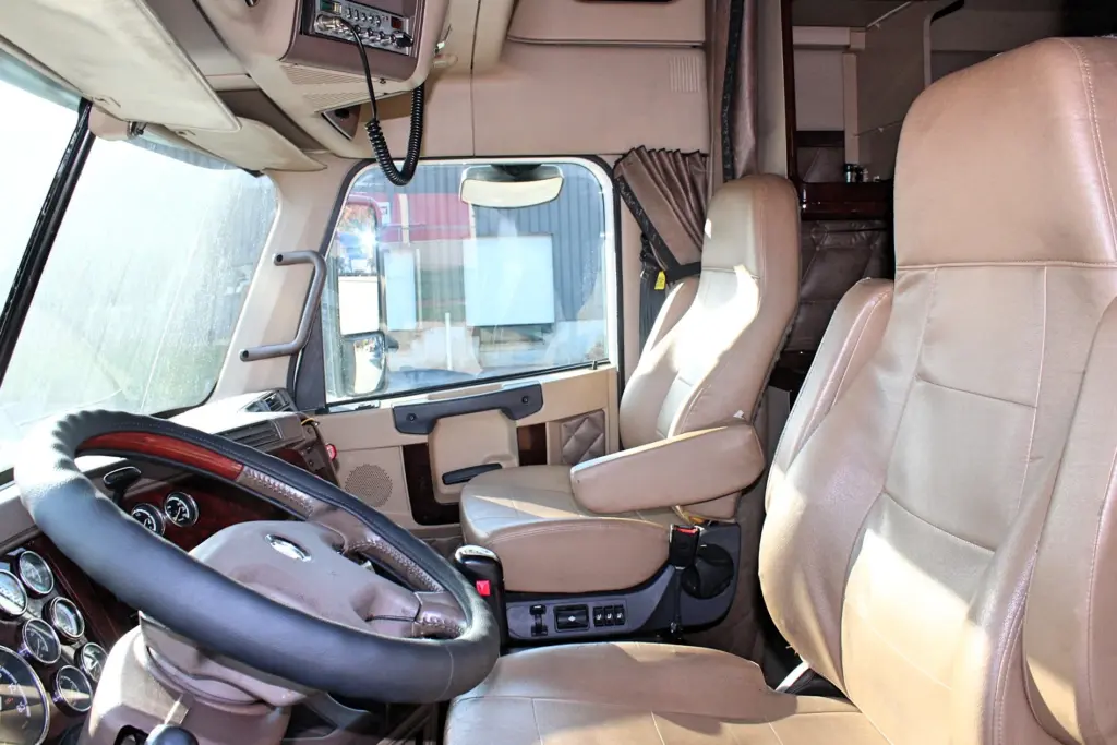 2018 Freightliner Coronado 132 — interior view of tan leather driver seat, wood-trim wheel and gauges