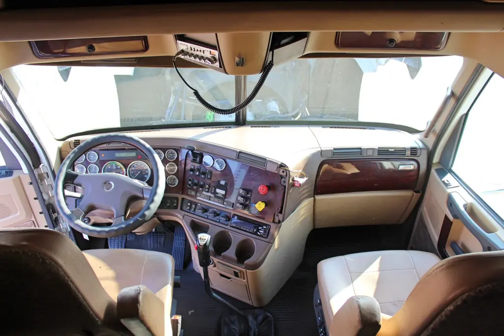 2018 Freightliner Coronado 132 — wide cab view over dash, gray steering wheel, tan seats and floor shifter
