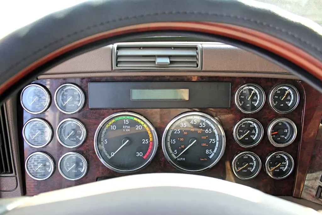 2018 Freightliner Coronado 132 — close view of gauge cluster with RPM and MPH dials framed by wood-grain trim