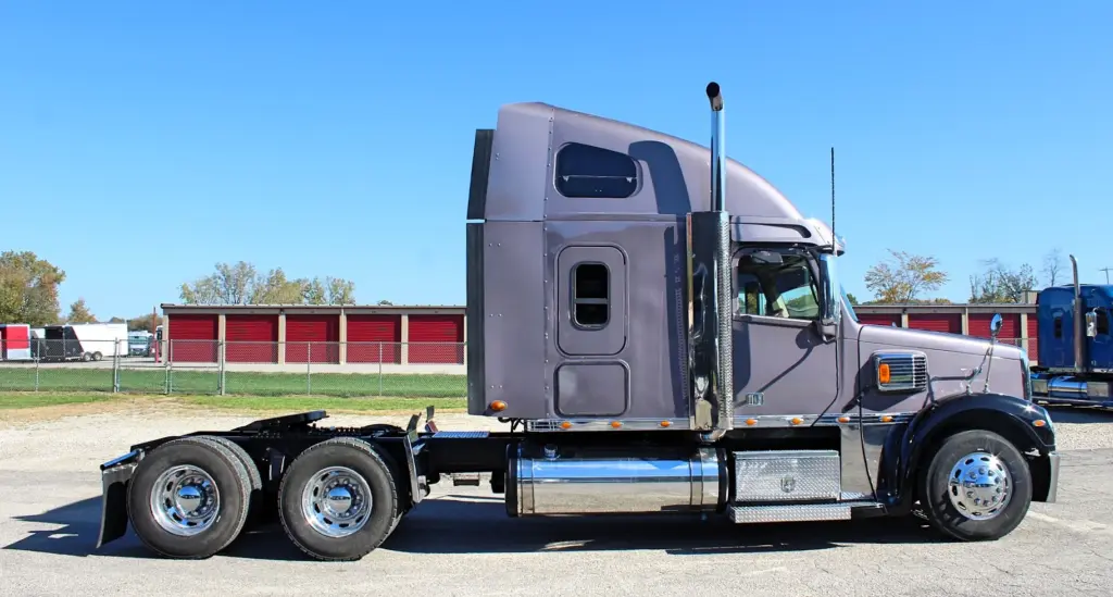 2020 Freightliner Coronado 132 — side profile of gray sleeper tractor with tall chrome stack and polished aluminum wheels