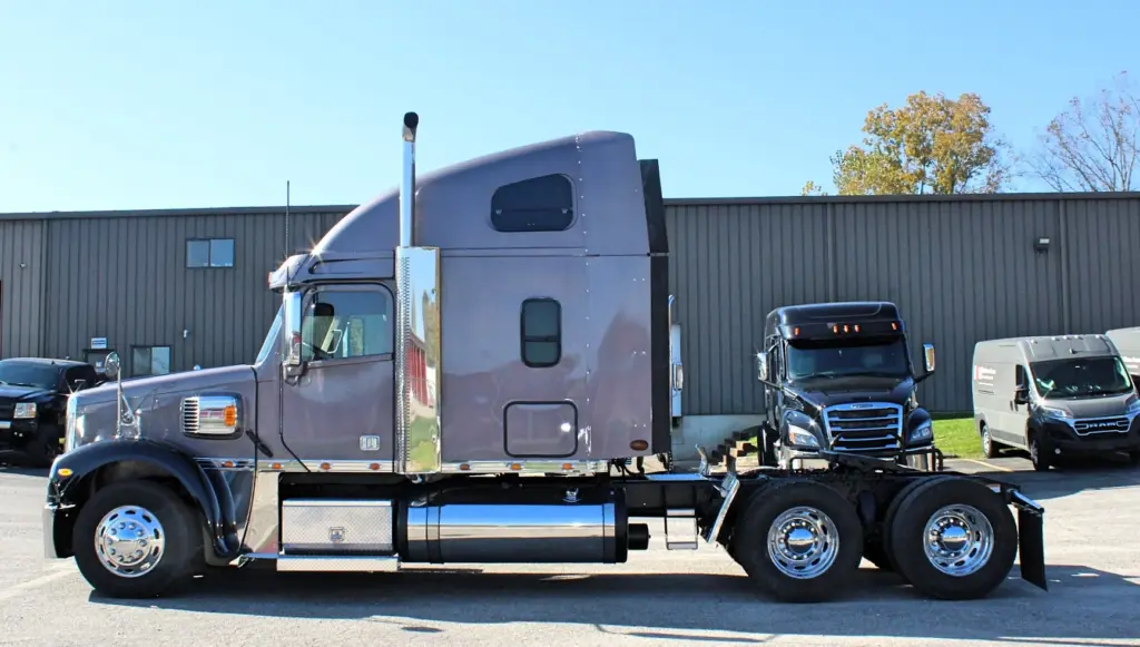 2020 Freightliner Coronado 132 — driver's side view of gray sleeper with chrome exhaust stack and polished aluminum wheels