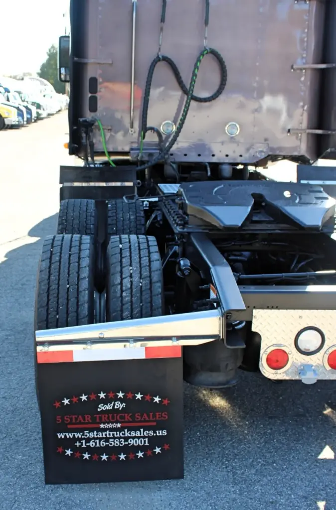 2020 Freightliner Coronado 132 — low close-up of rear tandem dual tires, black fuel tank and chrome-edged mud flap