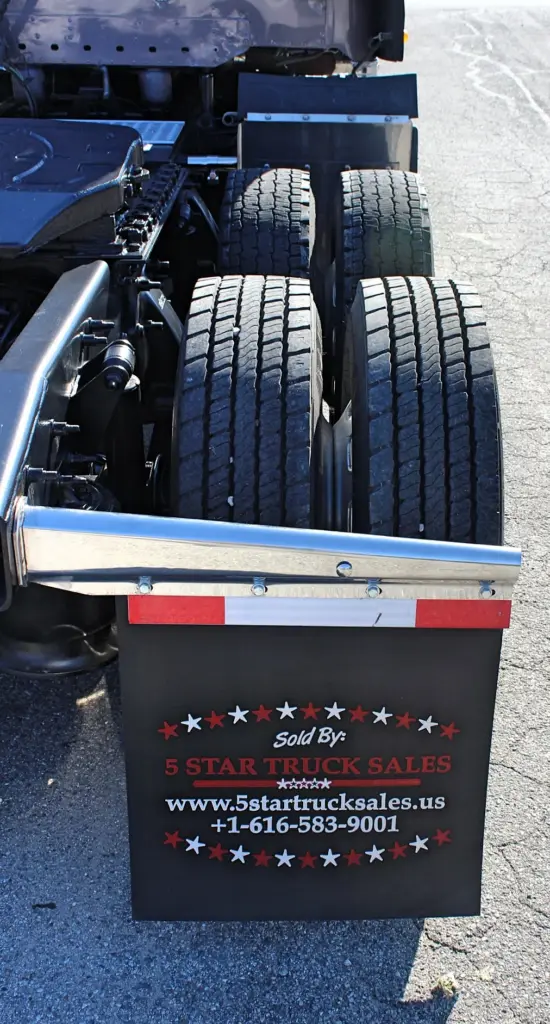 2020 Freightliner Coronado 132 — low rear view of dual tandem tires, chrome fender edge and black mud flap with stars