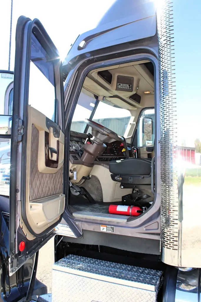 2020 Freightliner Coronado 132 — open driver door showing quilted tan panel and cab interior with red fire extinguisher