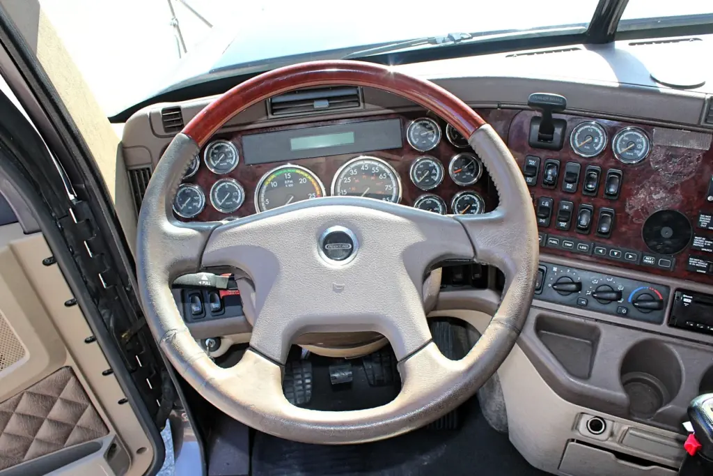 2020 Freightliner Coronado 132 — close view of tan and wood steering wheel with round gauges and dash switches