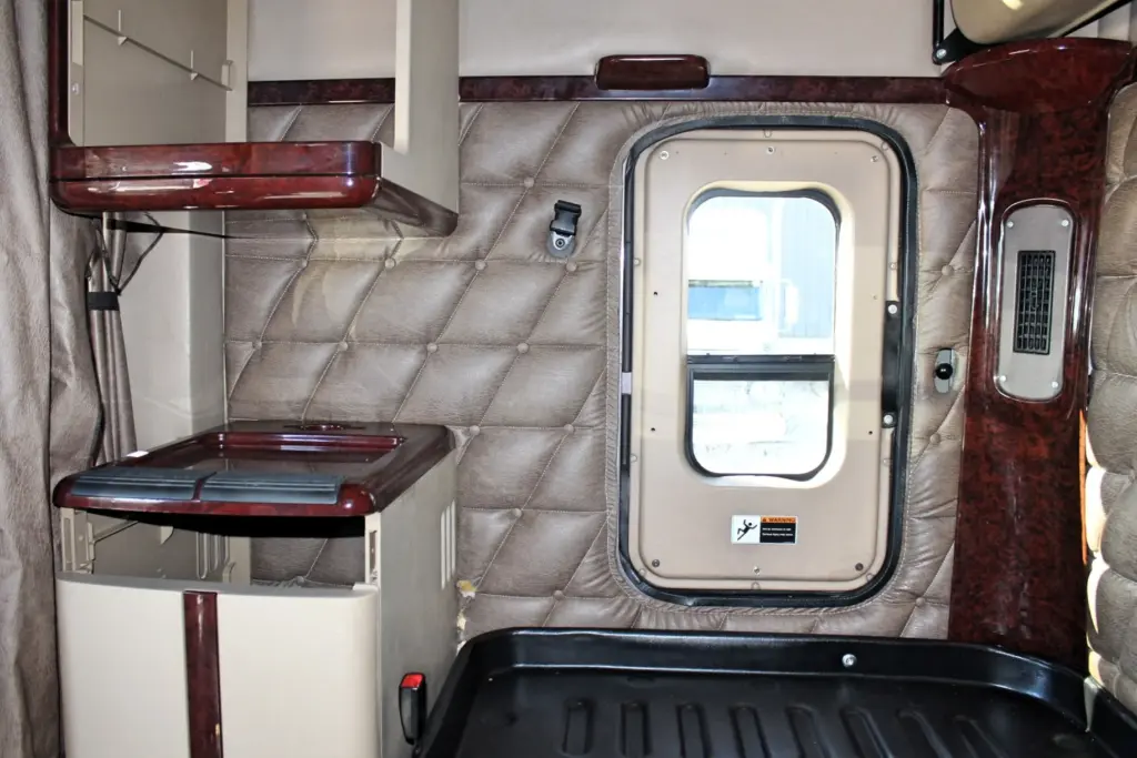 2020 Freightliner Coronado 132 — sleeper interior with diamond-stitched beige panel, wood-trim shelf and window in rear wall