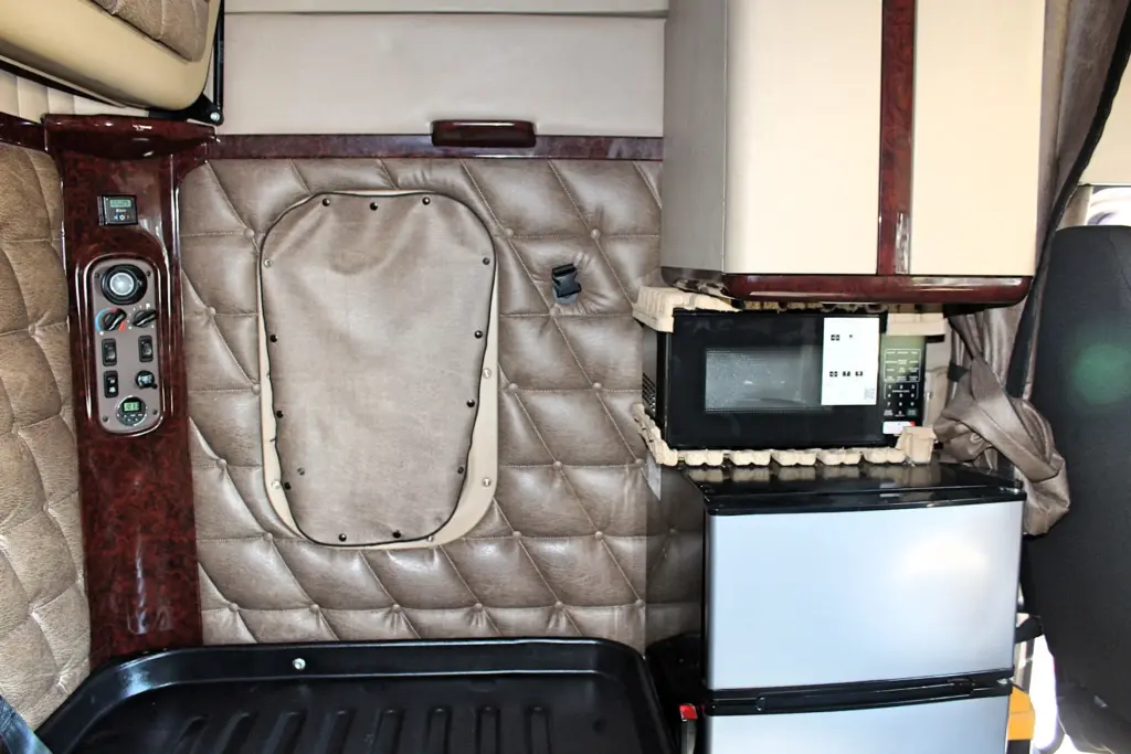 2020 Freightliner Coronado 132 — sleeper wall with microwave over mini fridge beside wood-trim switch panel