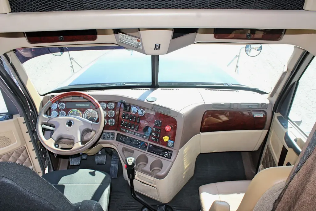2020 Freightliner Coronado 132 — windshield-facing cockpit view of burl-style dash, tan wheel and gear shifter