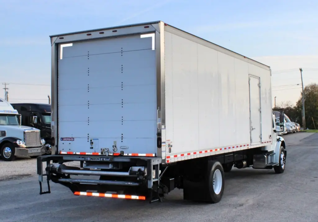 2020 Freightliner M2 106 — rear three-quarter view of white box truck with tail lift lowered and red reflective striping on box