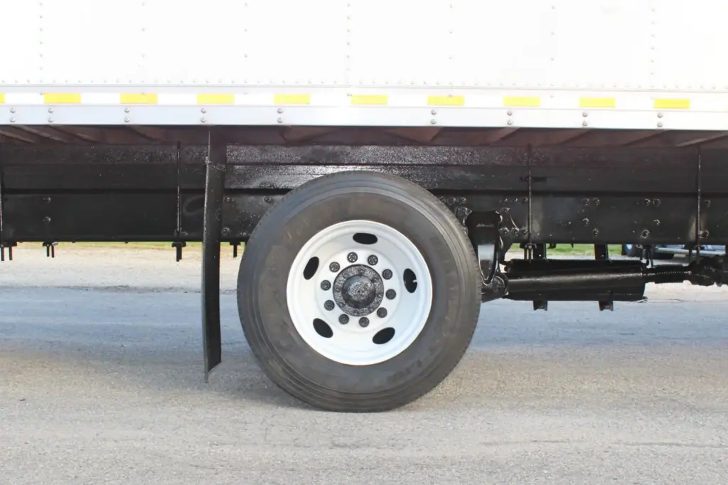 2020 Freightliner M2 106 — close-up of a white-rimmed wheel and tire under the box body, with black suspension visible.