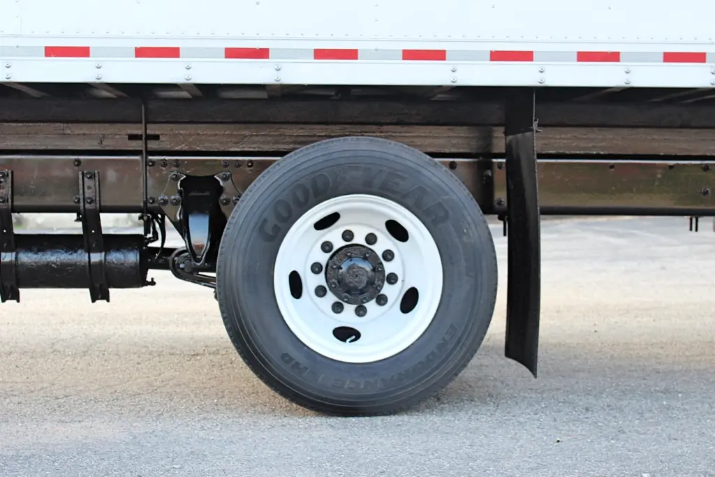 2020 Freightliner M2 106 — close-up of a Goodyear tire on white wheel under the box, with black mud flap and red reflectors