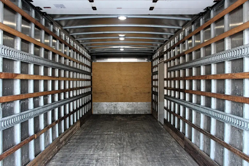 2020 Freightliner M2 106 — empty cargo box interior looking forward, wood side rails, plywood front wall and ceiling lights