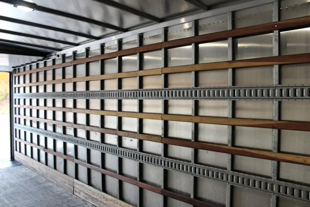 2020 Freightliner M2 106 — angled view down a box wall with horizontal wood battens, ribbed steel rails and open rear doorway