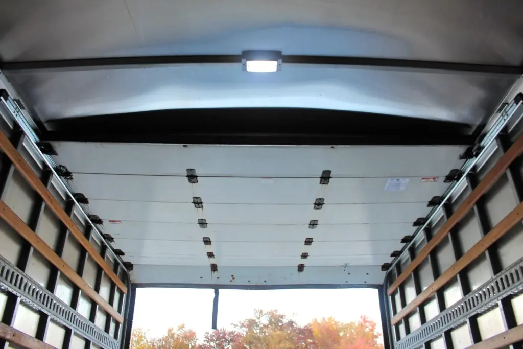 2020 Freightliner M2 106 — ceiling-up view of box, overhead light, tie-down anchors on front panel, trees through rear door