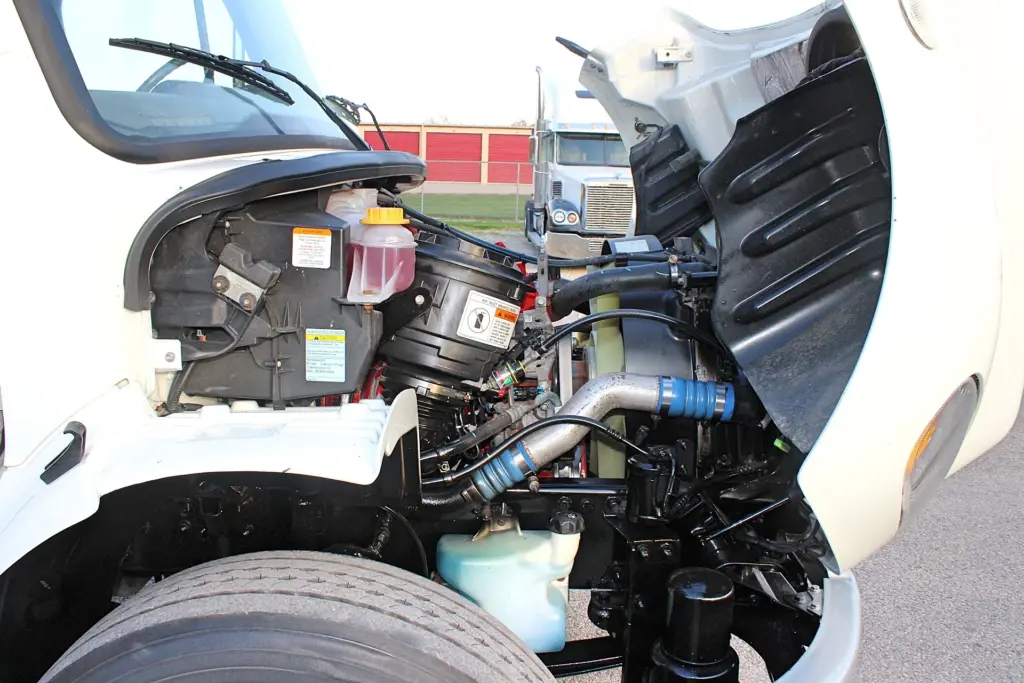 2020 Freightliner M2 106 — angled view into open hood showing blue charge-air hoses, fluid reservoirs and black engine bay